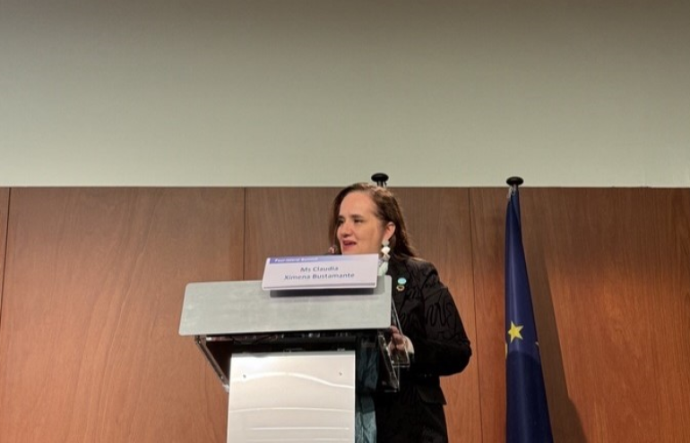 The image shows Claudia Ximena Bustamante during her speech at the 4-Lateral Summit 2025.