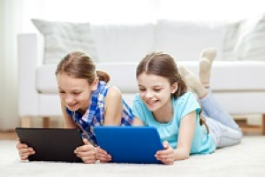 The image shows two children using tablets