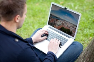 The image shows a person sitting in front of a laptop