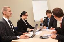 The image includes a group of young people sitting at a conference table and discussing