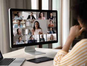 The image shows a woman sitting in front of the PC, participating in an online meeting.