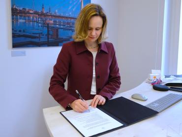 The image shows the Director of the BEREC Office, Verena Weber, signing the Green Charter.