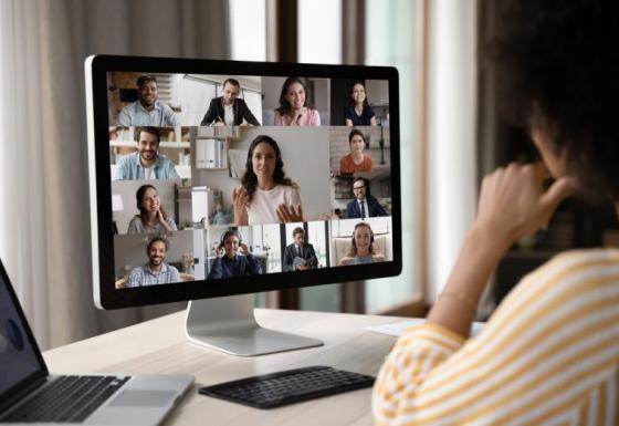 The image shows a woman sitting in front of the PC, participating in an online meeting.