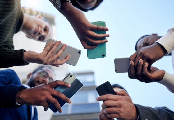 The image shows people with smartphones in their hands.