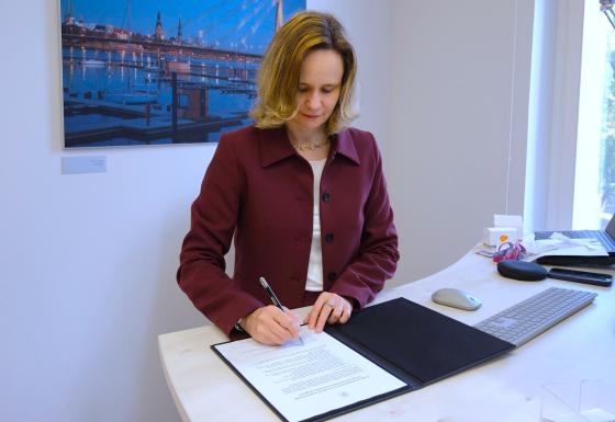 The image shows the Director of the BEREC Office, Verena Weber, signing the Green Charter.